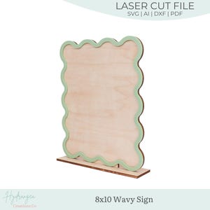 Puede incluir: Un letrero ondulado de madera de 20,3 x 25,4 cm con un borde y una base verde claro. El letrero es un archivo de corte láser, con el texto "LASER CUT FILE" y opciones de tipo de archivo. El letrero es de Hydrangea Creations Co.