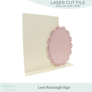 Puede incluir: Un letrero cortado con láser de color crema con un diseño ovalado de encaje rosa. El letrero es un rectángulo con una repisa y el texto "Lace Rectangle Sign". La parte superior del letrero tiene el texto "LASER CUT FILE".