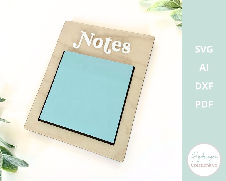May include: A wooden sign with the word "Notes" in white letters. The sign has a cutout for a sticky note, which is light blue.
