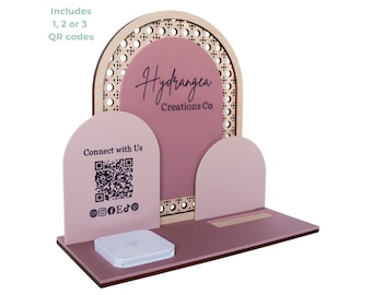 May include: A laser cut sign for a business, featuring a pink and wood design with a square reader and QR codes. The sign says "Hydrangea Creations Co" and "Connect with Us".