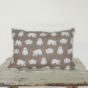 May include: A rectangular pillow with a brown linen fabric cover featuring a repeating pattern of white polar bears. The bears are in various poses, including standing, sitting, and lying down.