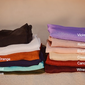 May include: A stack of fabric swatches in various colors, including black, white, burnt orange, navy, light teal, olive, violet, rose, blush, cream, candy apple, and wine.