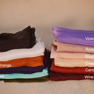 May include: A stack of fabric swatches in various colours, including black, white, burnt orange, navy, light teal, olive, violet, rose, blush, cream, candy apple, and wine.
