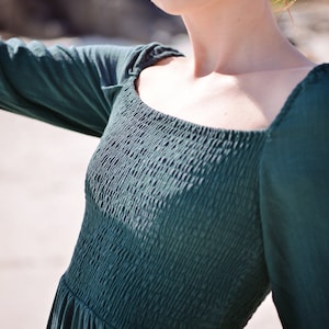 May include: A dark green, long-sleeved dress with a square neckline and a gathered bodice.