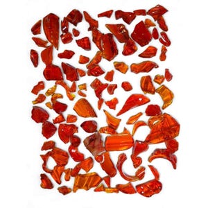 May include: A collection of irregularly shaped, translucent, red-orange glass pieces scattered against a white background. The pieces vary in size and shape, with some appearing more amber-toned than others. The overall effect is a vibrant, scattered display.