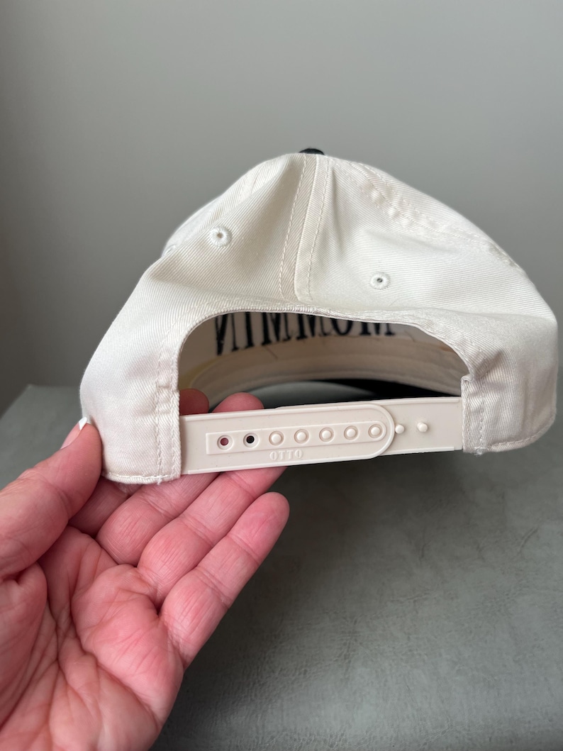 Puede incluir: Gorra de b&eacute;isbol color crema con visera negra y la palabra "VINTAGE" impresa en negro en la parte inferior de la visera. La gorra tiene una correa ajustable blanca con la marca "OTTO" impresa.