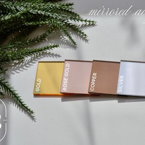 Pu&ograve; includere: Campioni di acrilico a specchio dorato, oro rosa, rame e argento. I campioni sono rettangolari e disposti in fila. Le parole "GOLD", "ROSE GOLD", "COPPER" e "SILVER" sono stampate su ogni campione.