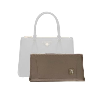 Könnte beinhalten: Ein brauner Filz-Handtaschenorganizer mit einem kleinen Logo unten rechts. Der Organizer ist so konzipiert, dass er in eine größere Handtasche passt.