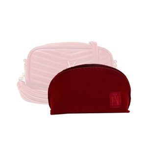 Peut inclure: Un sac en velours rouge avec un logo doré et un pompon rouge. Le sac est conçu pour tenir dans un petit sac à main.