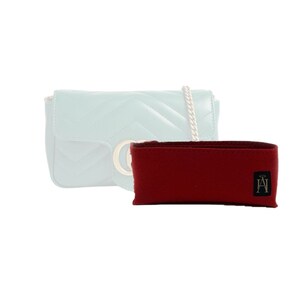 Peut inclure: Un insert de sac en feutre rouge avec un petit logo noir comportant les lettres "A" et "H". L'insert est conçu pour s'adapter à l'intérieur d'un sac à main matelassé.