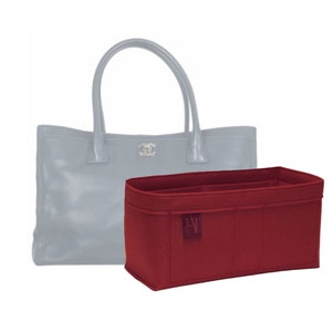 Könnte beinhalten: Ein roter Filz-Taschen-Einsatz mit mehreren Fächern und einer kleinen Tasche mit dem Buchstaben "A" in Weiß. Der Einsatz ist so konzipiert, dass er in eine Tragetasche passt.