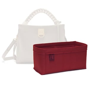 Peut inclure: Un insert de sac en feutre bordeaux avec plusieurs compartiments et un petit logo "A". L'insert est conçu pour s'adapter à l'intérieur d'un sac à main afin d'aider à organiser l'intérieur.