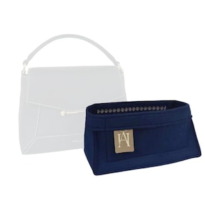 May include: A navy blue felt bag insert with a small brown label that says "LA" in a script font. The insert is designed to fit inside a handbag to help organise the contents.