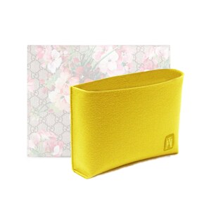 Peut inclure: Un sac en feutre jaune avec un monogramme GG et une doublure à imprimé floral. Le sac est conçu pour s'insérer dans un sac à main plus grand.