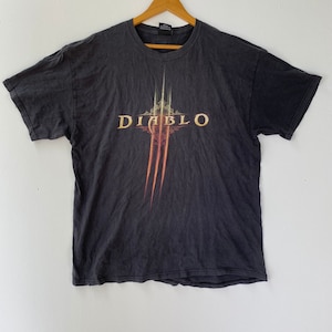 May include: A black t-shirt with a faded graphic print of the word "Diablo" in gold lettering with a stylized claw design.