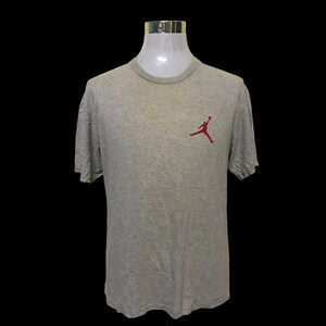 Op de afbeelding: Een grijs T-shirt met korte mouwen en een rood Jumpman-logo op de linkerborst.