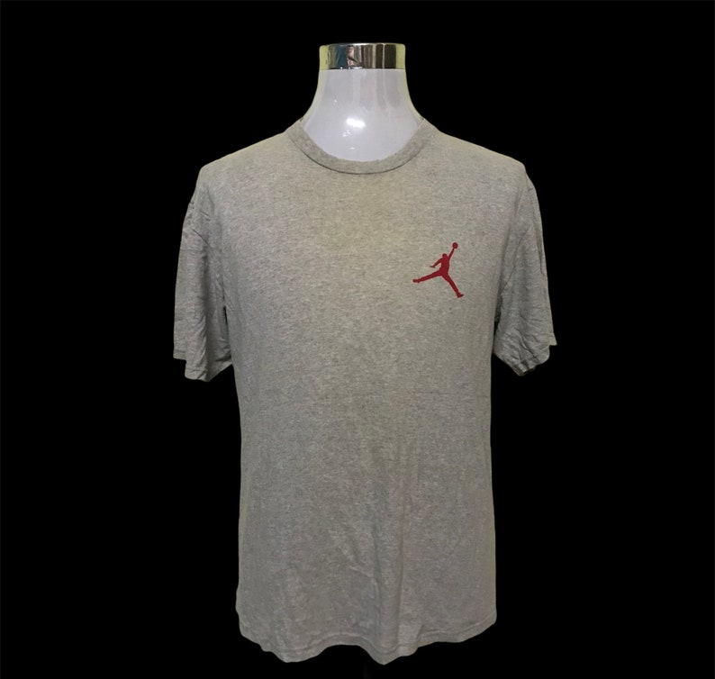 Op de afbeelding: Een grijs T-shirt met korte mouwen en een rood Jumpman-logo op de linkerborst.