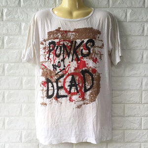 May include: White t-shirt with a brown and red graphic print that says "Punks Not Dead" with a peace sign.
