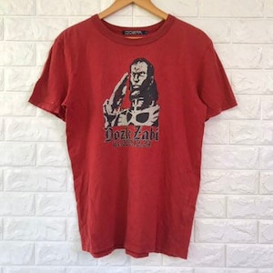 Puede incluir: Camiseta roja de manga corta con un estampado gráfico de un hombre con barba y una corona. El texto "Doze Zahi" está impreso debajo del gráfico.