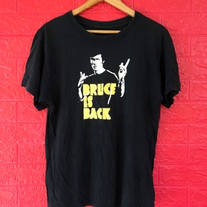 May include: Black t-shirt with a yellow graphic of Bruce Lee with the text "Bruce is Back".