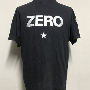May include: Black t-shirt with a silver print of the word "ZERO" and a star.