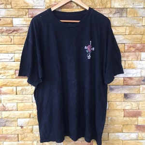 May include: Black t-shirt with a graphic of a rose and cross on the front.