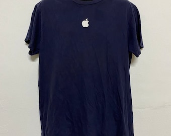 May include: A navy blue t-shirt with a white Apple logo on the front.