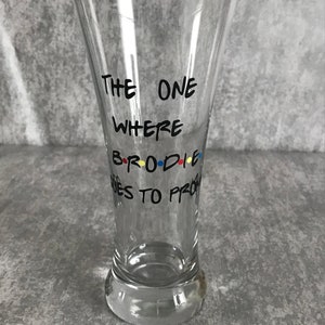 May include: Clear glass beer mug with black text that reads "The One Where..." and "...Goes to Prom" with colourful dots around the word "Brodie".