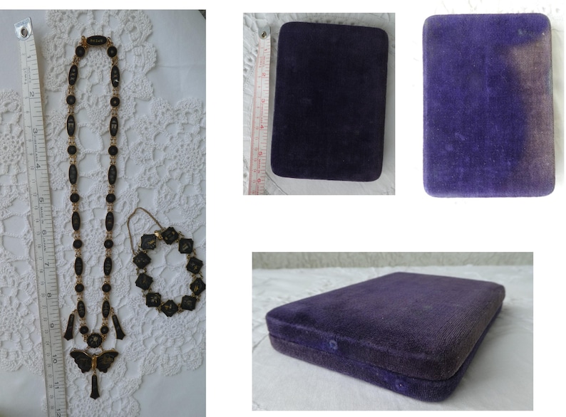 Op de afbeelding: Een zwarte en gouden ketting- en armbandset met een vlinderhanger. De set wordt getoond op een witte kant achtergrond en wordt geleverd in een paarse fluwelen doos.