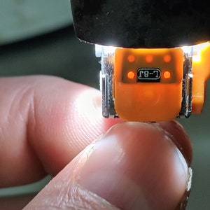 May include: Close-up of an orange electrical connector with the text "T-8" printed on it. The connector has five small, round, red lights.