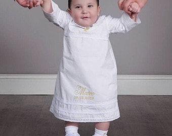 May include: A white baby gown with a lace trim and embroidered with the name "Mateo" and the date "10.12.2019".