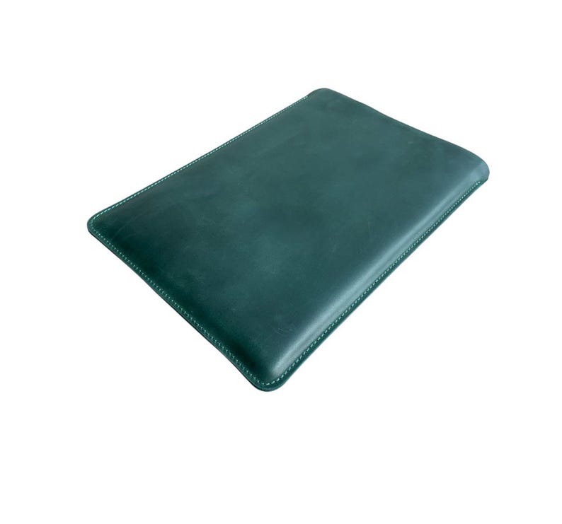 K&ouml;nnte beinhalten: Eine dunkelgr&uuml;ne Lederh&uuml;lle mit wei&szlig;en N&auml;hten an den Kanten. Die rechteckige H&uuml;lle ist f&uuml;r ein Tablet oder ein &auml;hnliches Ger&auml;t konzipiert. Das Leder hat eine leicht strukturierte Oberfl&auml;che.