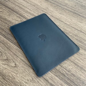 May include: A dark blue leather sleeve with a stitched edge and an Apple logo embossed on the front.
