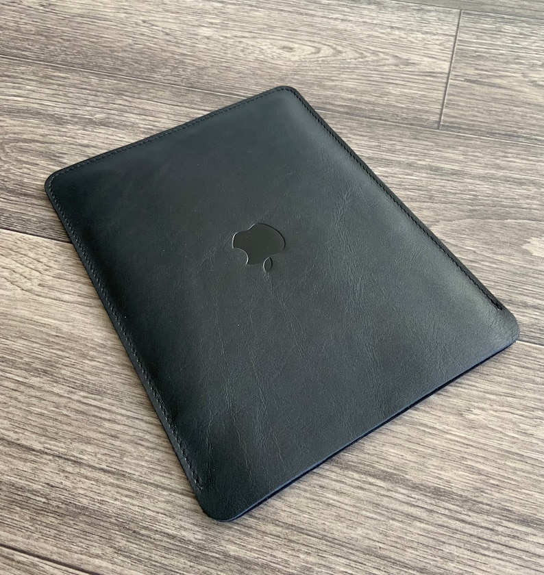 May include: Black leather sleeve with a stitched edge and an Apple logo in the center.