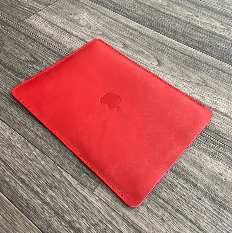 May include: Red leather laptop sleeve with an Apple logo embossed on the front.