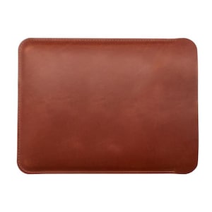 K&ouml;nnte beinhalten: Eine rechteckige, braune Lederh&uuml;lle mit abgerundeten Ecken. Die H&uuml;lle ist einfarbig und scheint an den R&auml;ndern gen&auml;ht zu sein. Das Leder hat eine glatte, matte Oberfl&auml;che. Die H&uuml;lle ist f&uuml;r ein Tablet oder einen Laptop konzipiert.