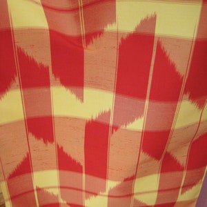 May include: Red and yellow fabric with a checkered pattern. The fabric has a subtle ikat design with a woven texture.