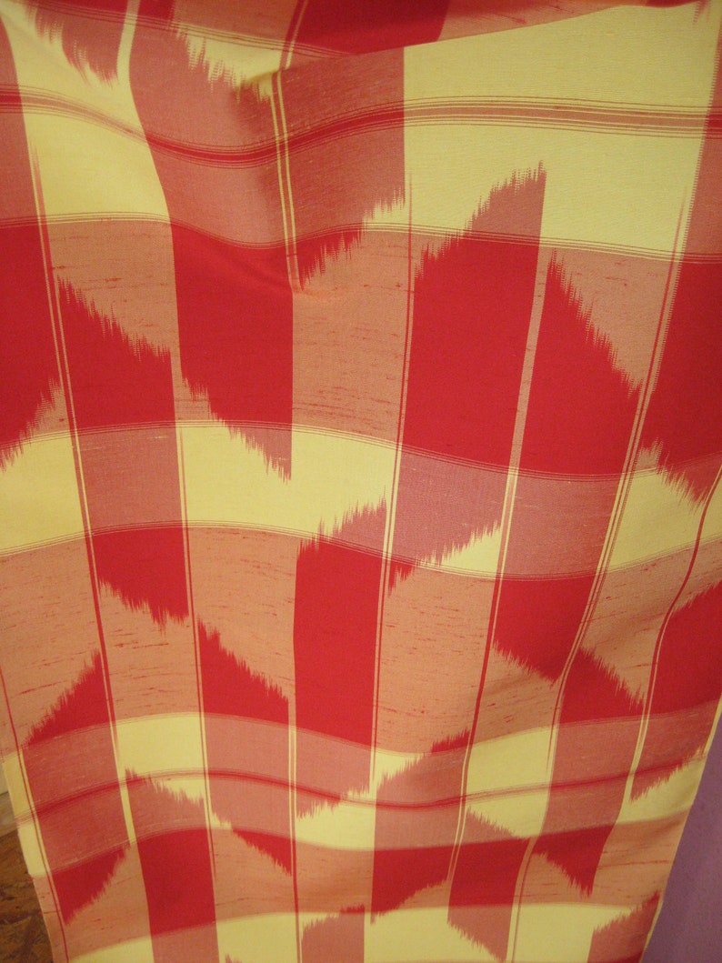 May include: Red and yellow fabric with a checkered pattern. The fabric has a subtle ikat design with a woven texture.