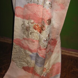 May include: A pink and white silk kimono with gold and silver embroidery of flowers and waves. The kimono has a traditional Japanese design.