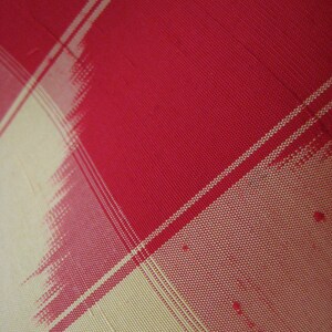 May include: Red and cream checkered fabric with a woven texture.