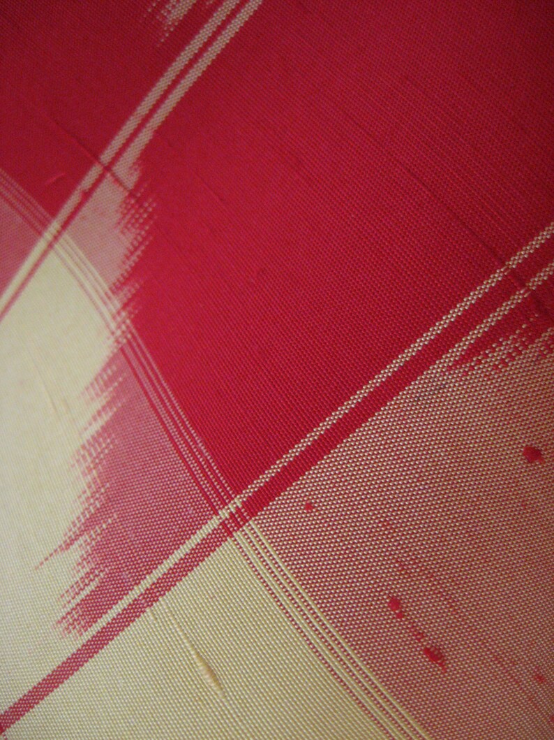 May include: Red and cream checkered fabric with a woven texture.