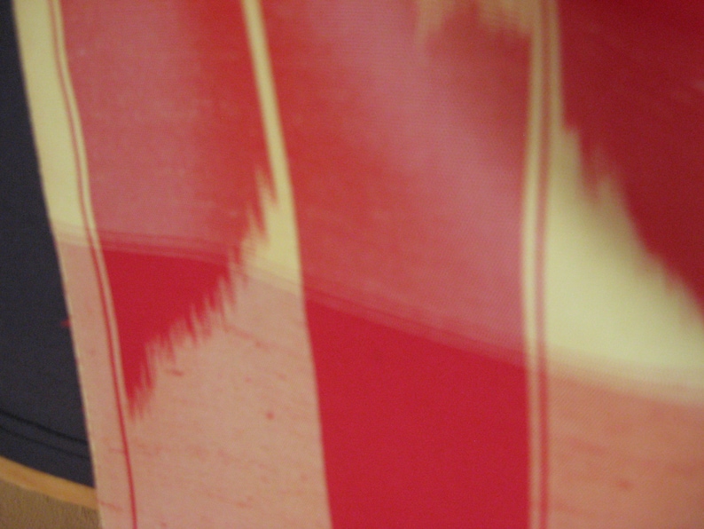 May include: A close-up of a red and cream striped fabric. The fabric has a subtle, textured pattern.