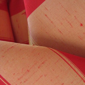 May include: Red and cream striped fabric with a woven texture. The fabric is folded and shows the pattern.