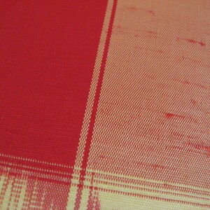 May include: Red and yellow plaid fabric with a woven texture.