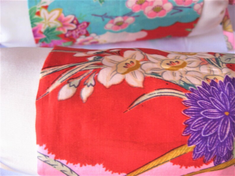 May include: Close-up of a red fabric with a floral pattern. The fabric features white, pink, and purple flowers with green leaves. The fabric is likely intended for quilting or crafting.