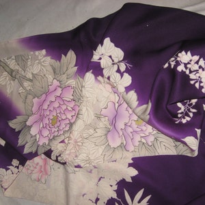 May include: A deep purple kimono with a floral design. The fabric features large, light pink peonies and white flowers with gray leaves. The kimono's design is a blend of traditional Japanese art and modern fashion.