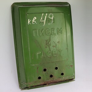 Puede incluir: Un buzón de metal verde con una ranura para cartas y una ranura más pequeña para periódicos. El buzón tiene el texto "кв. 4/9 ПИСЕМ И ГАЗЕТ" escrito en él.