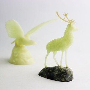 May include: A pair of vintage figurines, a deer and a bird, made of a translucent green material. The deer is standing on a small, dark green base.