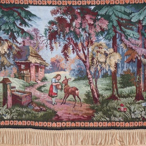 May include: A tapestry depicting a whimsical woodland scene with a small cottage, a girl feeding a deer, and a well with a bucket. The tapestry has a fringe border and features a variety of colours, including green, blue, brown, and pink.
