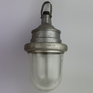 May include: A silver metal hanging light fixture with a clear glass shade. The fixture has a number "200-00193" printed on it.